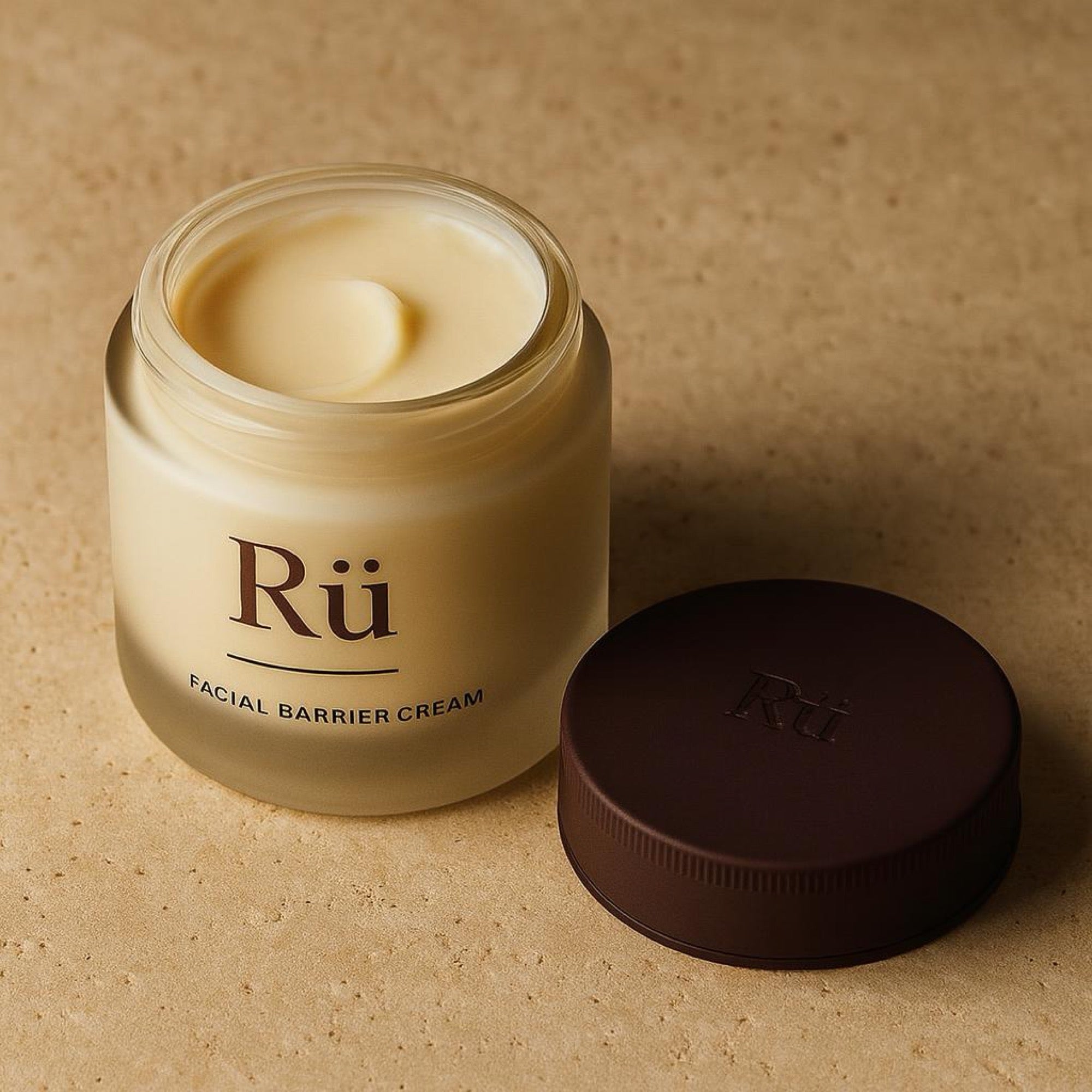 The Rü jar open, the debossed lid lying beside it, cream filled flush to the rim